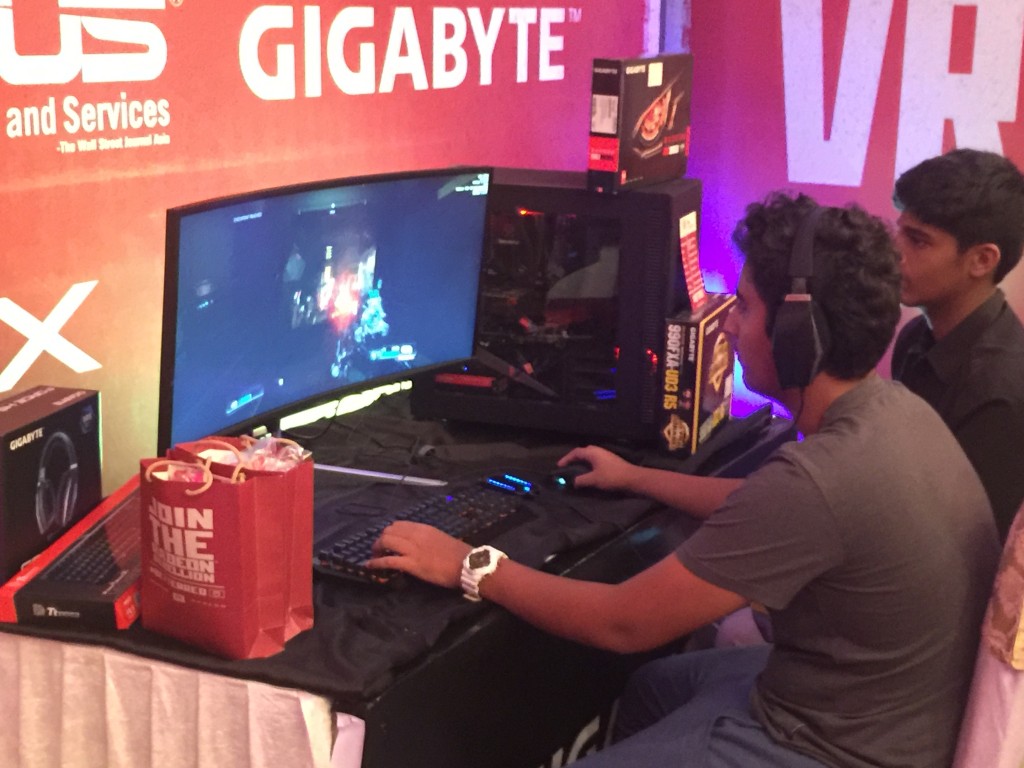 Picture of a gamer at the event surrounded by the “better red” and “rebellion” branding of AMD playing a game on PC that’s a custom rig with the just-launched H5 Surround Sound Headphones